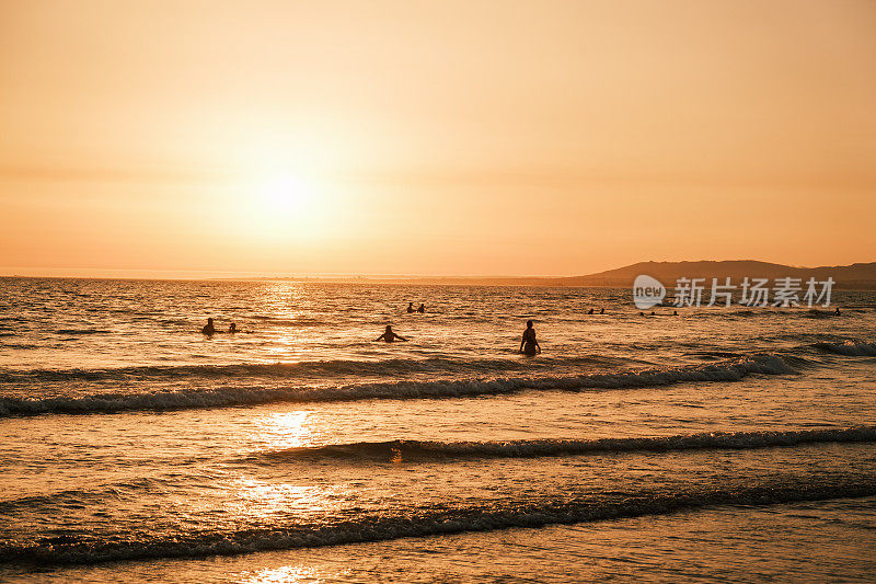 在葡萄牙里斯本附近的Costa da Caparica，日落时海面上的人的剪影